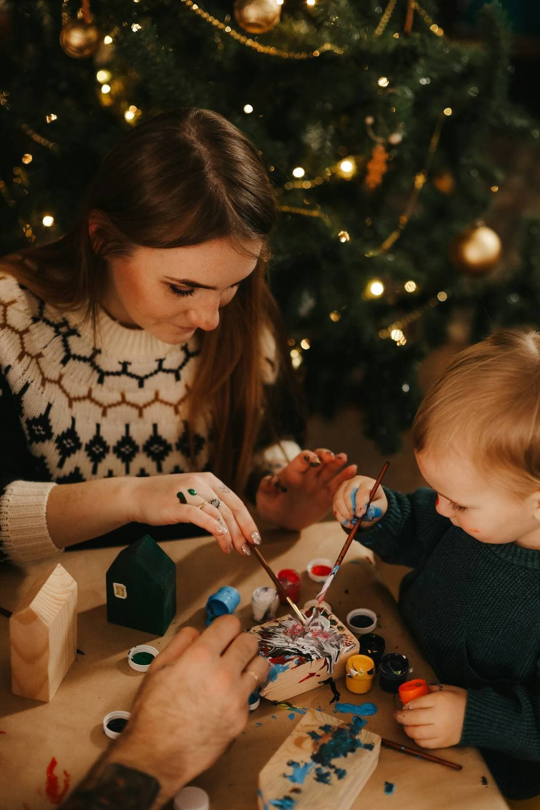 Kind bastelt mit einer Erwachsenen am Weihnachtsbaum