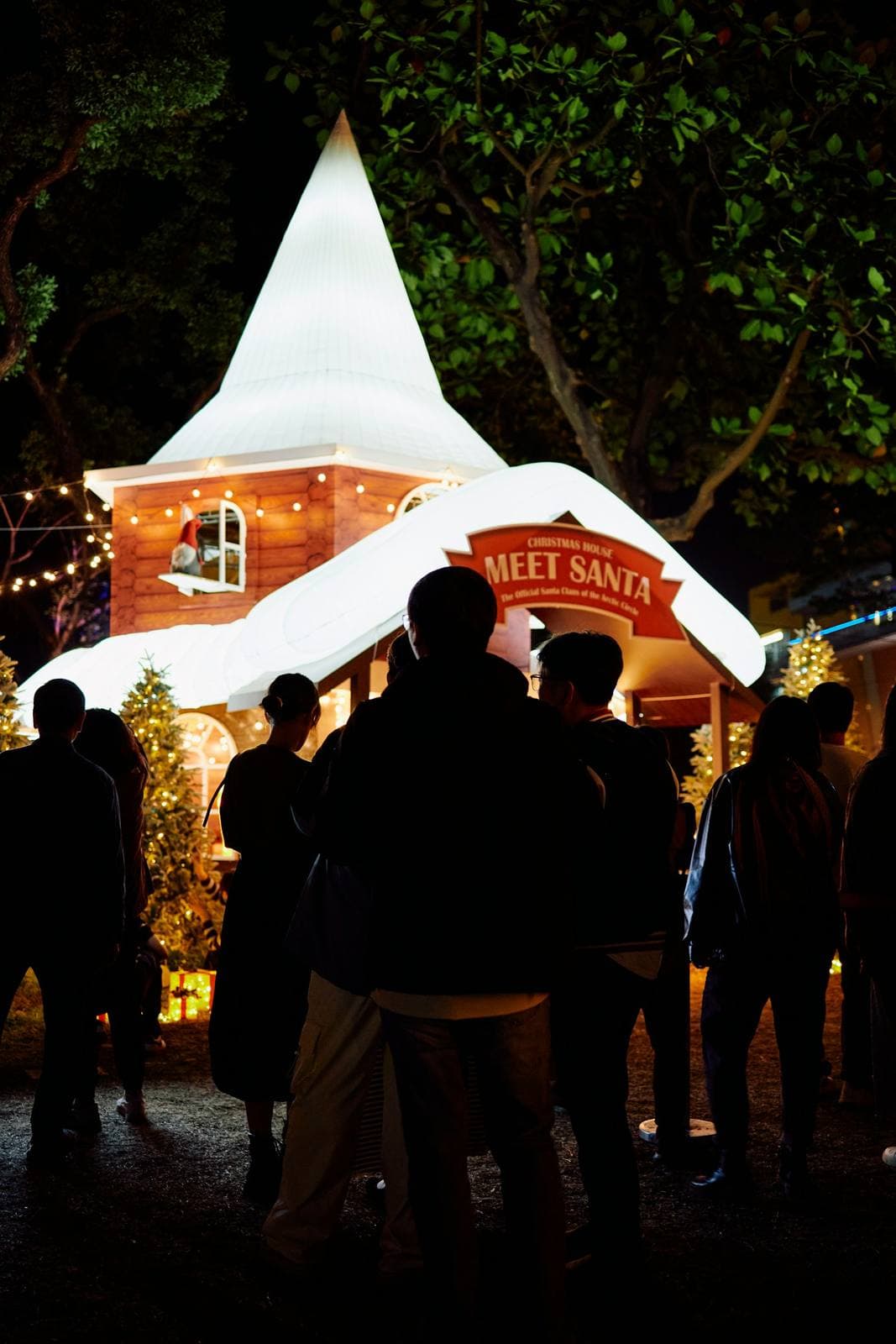 Familien vor einem beleuchteten Häuschen auf dem Weihnachtsmarkt